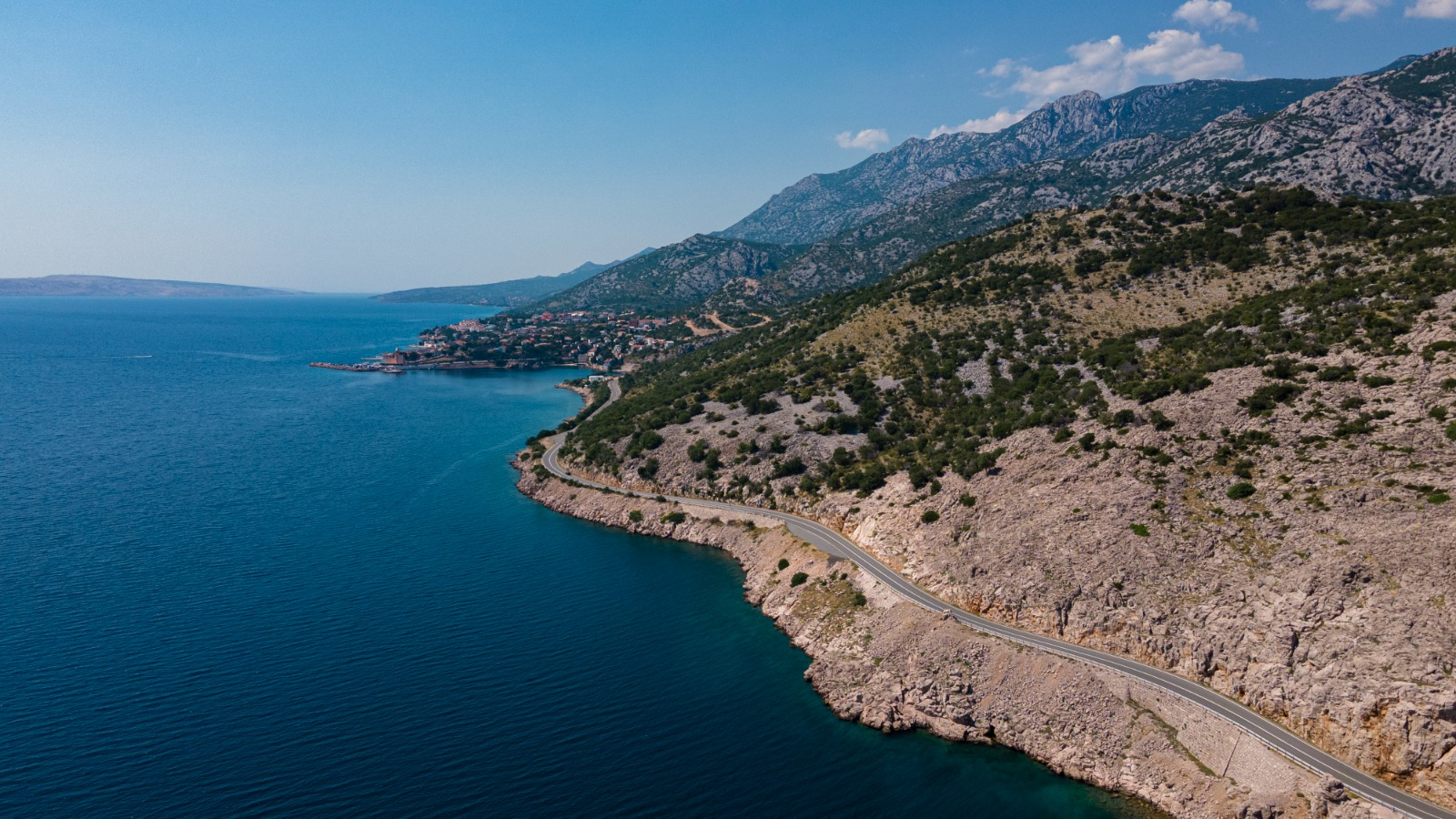 Remote Balkan coastal road beside clear blue water
