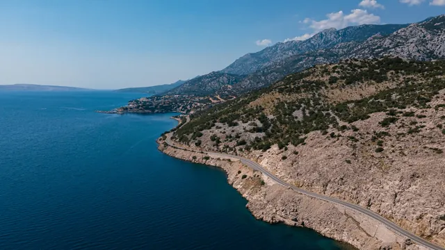 Remote Balkan coastal road beside clear blue water